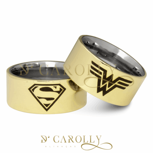 Modelo: 398 / 399 Largura: 10 mm Espessura: 2 mm Material: Liga de moeda antiga Acabamento Externo: Reta, polida com gravação a laser de mulher maravilha e superman. Acabamento Interno: Forrada em aço inox, hipoalergênico, anatômica. Descrição: Aliança de casamento ou noivado, personalizada, grossa, produzida liga de moeda antiga com gravação a laser de símbolos da Mulher Maravilha e Superman na parte externa. Na parte interna acabamento em aço inox, anatômico, hipoalergênico. Este material demanda alguns cuidados, esta liga tende a oxidar com o tempo, a limpeza e manutenção periódica do material fazem com que mantenham sua beleza constante.